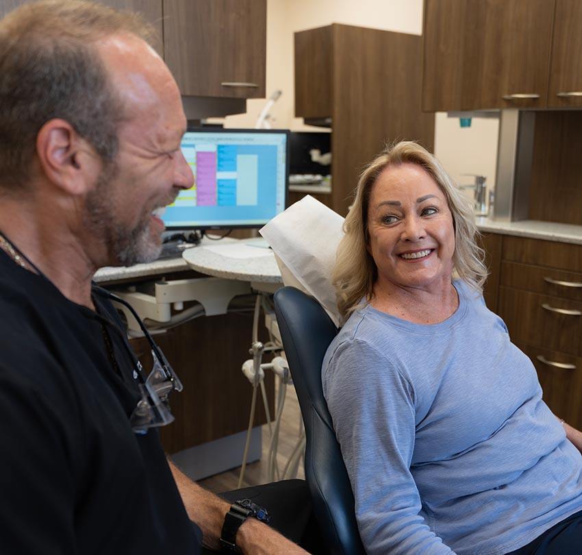 A seated older female patient smiles to Dr. Owen M. Waldman