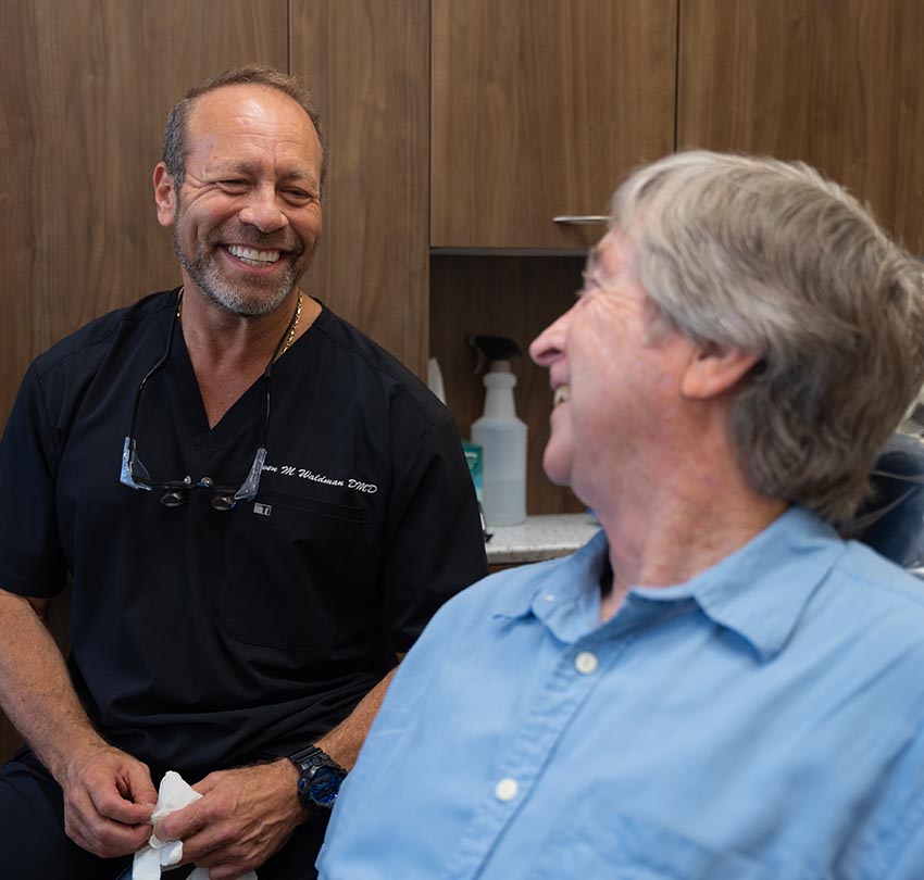 Dr. Owen M. Waldman smiles to a seated older male patient