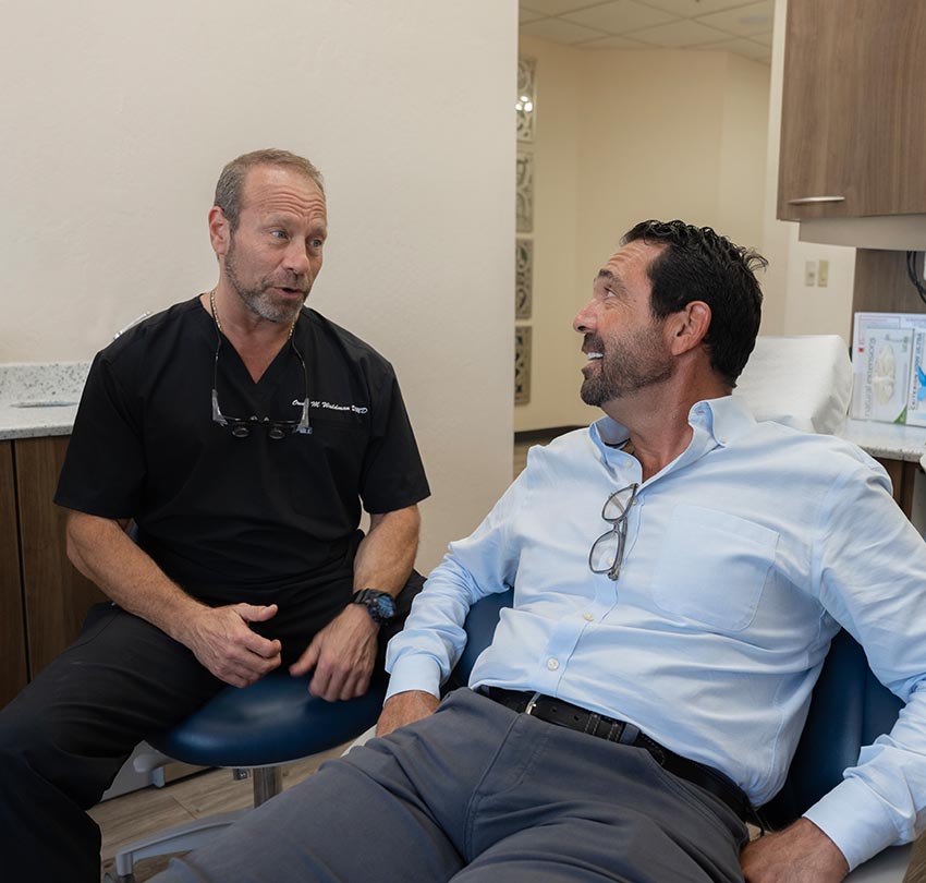 Dr. Owen M. Waldman chats up a male dental patient seated inside his clinic