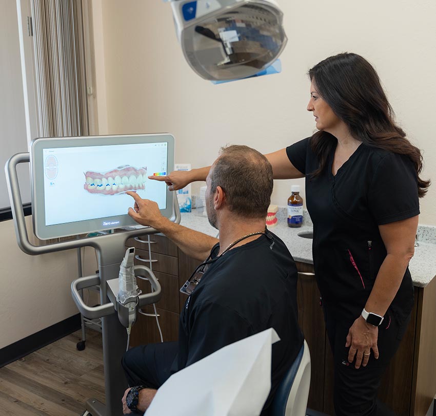 Dr. Owen M. Waldman and a female staff points to a dental image in the computer