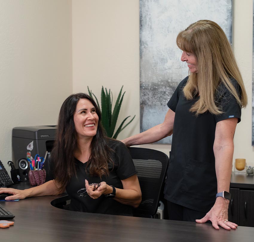 two female dental staff members at Waldman Dental Group smiles to each other